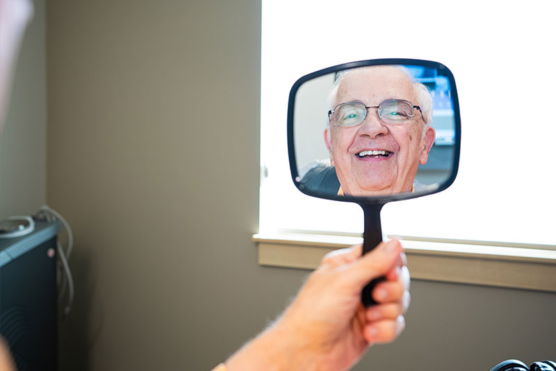 patient smiling brightly while looking in the mirror